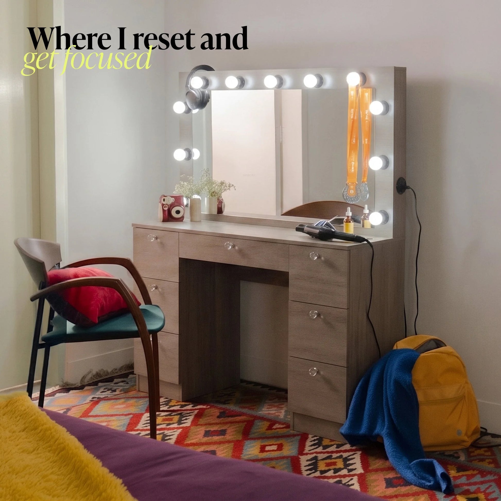 Wooden vanity with illuminated mirror in a room with colorful rug and chair.