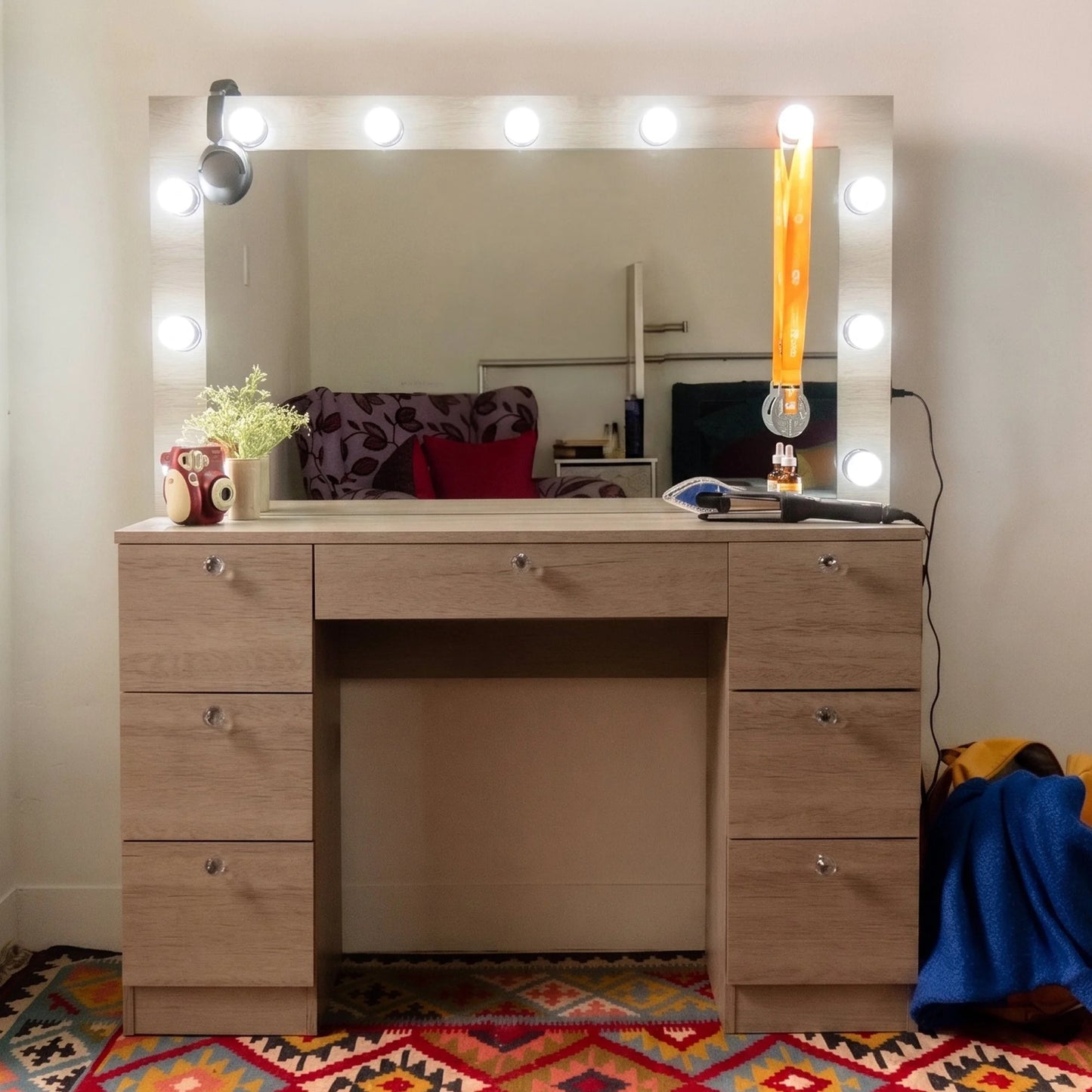 Wooden vanity with mirror and lights in a room with colorful rug